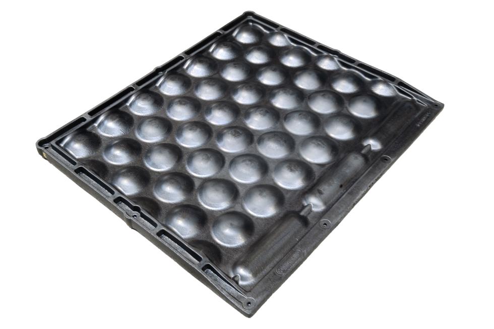 Ein schwarzes Tiefboxenkissen aus Gummi mit kugelartiger Ausstülpungen auf der Oberseite, gefüllt mit Luft, erhöhter Rand hinten und seitlich, pillenartige Ausstülpungen am vorderen Rand, dicker als h